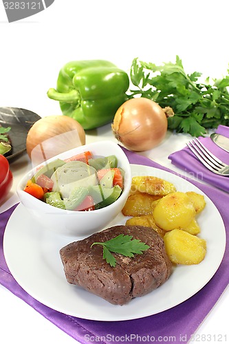 Image of Ostrich steaks with baked potatoes and vegetables
