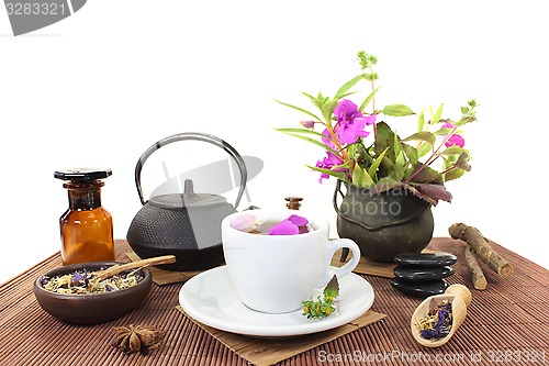 Image of Chinese natural medicine with a cup of tea and blossoms