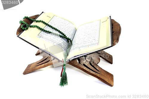 Image of stand with an opened Quran and rosary