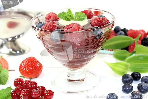 Image of red fruit jelly with custard and raspberries