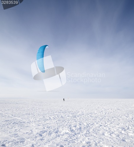 Image of Kiteboarder with blue kite on the snow