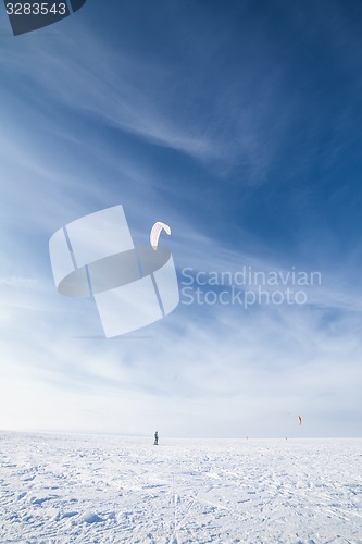 Image of Kiteboarder with blue kite on the snow