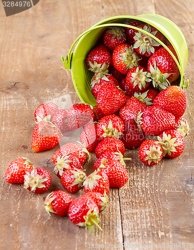 Image of strawberry in a green metal bucket on wooden