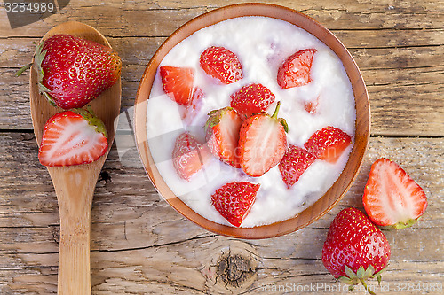 Image of fresh organic greek yogurt with strawberries on wooden 