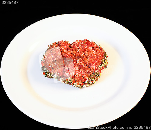 Image of Seasoned raw red hamburger on white plate isolated on black