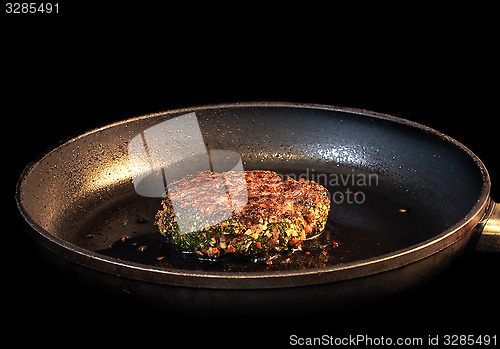 Image of Frying seasoned hamburger in fry pan isolated on black
