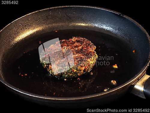 Image of Frying seasoned hamburger in fry pan isolated on black