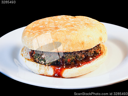 Image of Closeup of juicy hamburger between buns with delicious red sauce