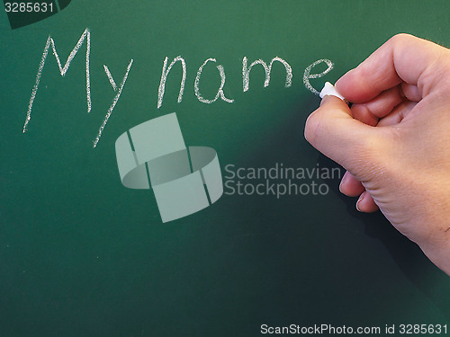 Image of Person writing on green chalkboard; My name, with calk