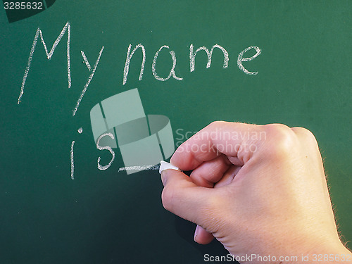 Image of Teacher writing on green chalkboard: My name is