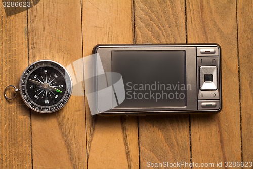 Image of smartphone and compass on wooden background