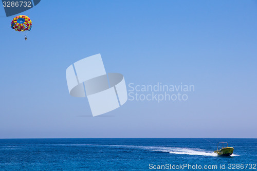 Image of Parachute with people fly under motor boat