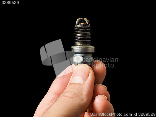Image of Hand of a male person holding a worn spark plug isolated on blac