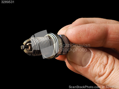 Image of Closeup of a worn spark plug held by caucasian male fingers