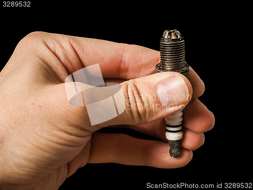 Image of Closeup of a worn spark plug held by caucasian male fingers