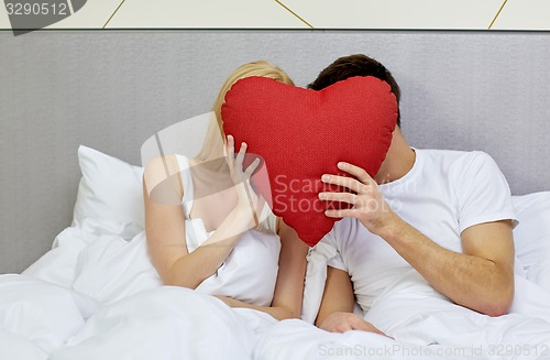 Image of happy couple in bed with red heart shape pillow