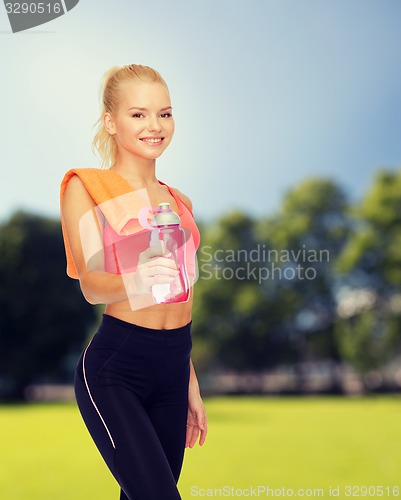 Image of smiling sporty woman with water bottle and towel