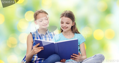 Image of two happy girls reading book over green background