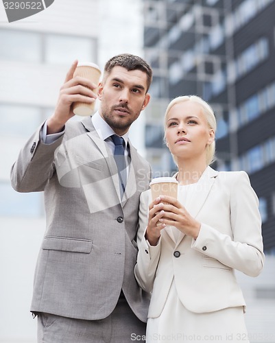 Image of serious businessmen with paper cups outdoors