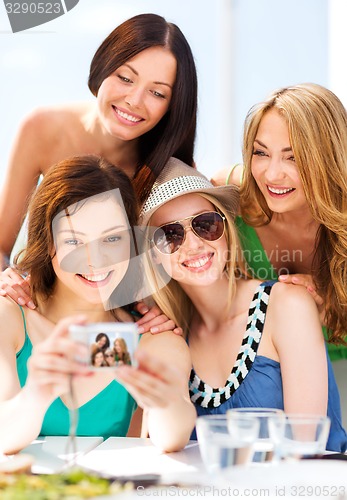 Image of girls taking photo in cafe on the beach