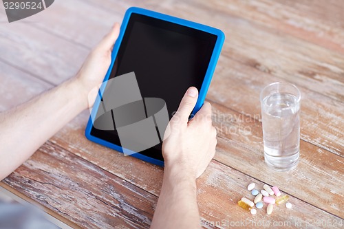 Image of close up of hands with tablet pc, pills and water