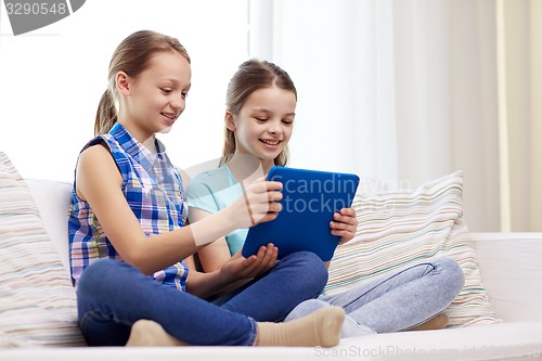 Image of happy girls with tablet pc sitting on sofa at home