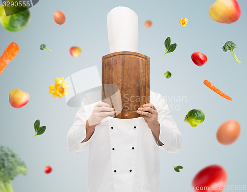 Image of male chef cook covering face with cutting board