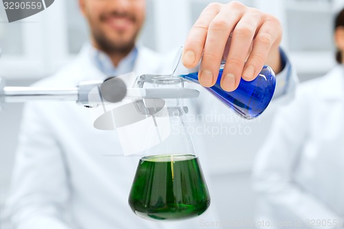 Image of close up of scientist filling test tubes in lab