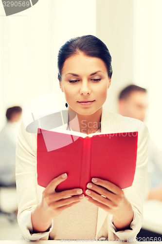 Image of woman reading book in college or office