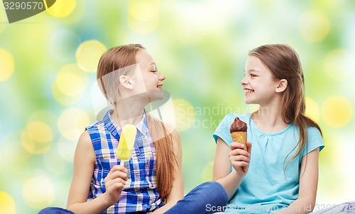 Image of happy little girls eating ice-cream over green