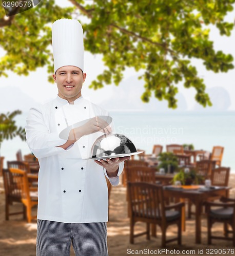 Image of happy male chef cook holding cloche