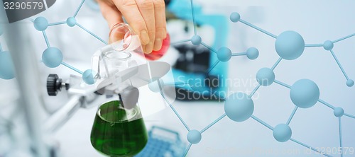 Image of close up of scientist filling test tubes in lab