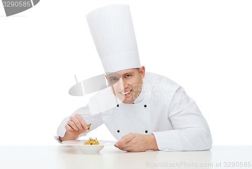 Image of happy male chef cook decorating dish