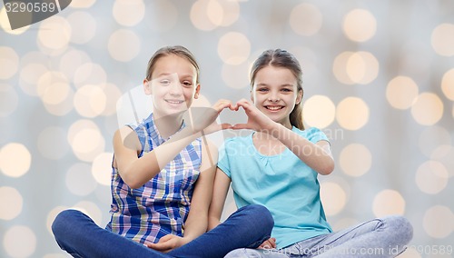 Image of happy little girls showing heart shape hand sign