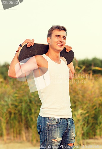 Image of smiling teenage boy with skateboard outdoors