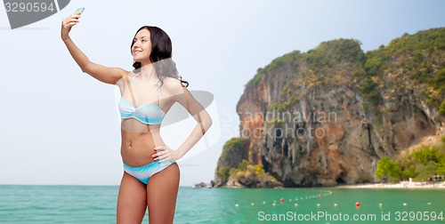 Image of woman in swimsuit taking selfie with smatphone