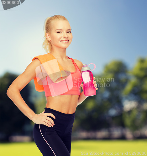 Image of smiling sporty woman with water bottle and towel