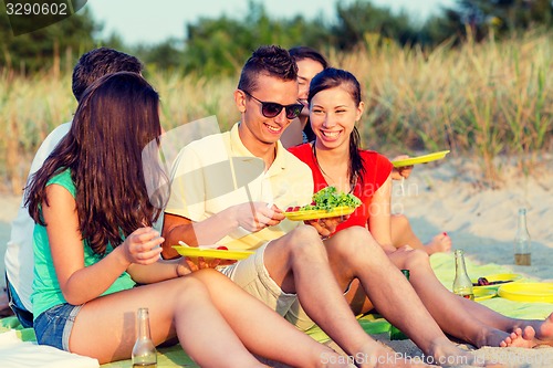Image of smiling friends sitting on summer beach