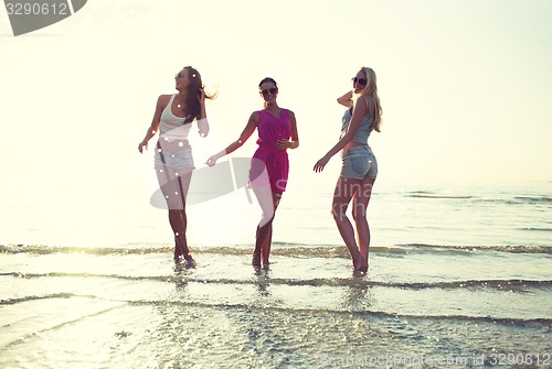 Image of happy female friends dancing on beach