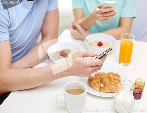 Image of close up of couple with smartphones at breakfast