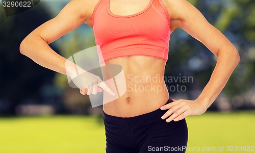Image of close up of woman pointing finger at her six pack