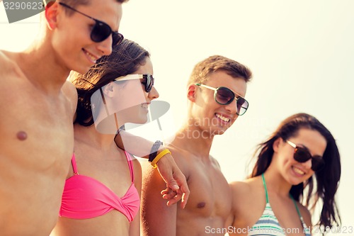 Image of smiling friends in sunglasses on summer beach