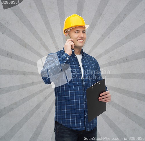 Image of smiling male builder in helmet with clipboard