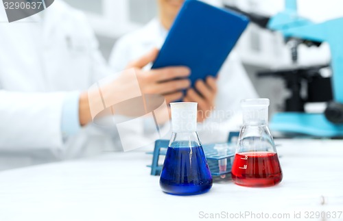 Image of close up of scientists with flasks and tablet pc