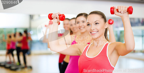 Image of group of smiling people working out with dumbbells