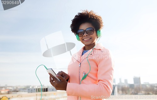 Image of happy young woman with smartphone and headphones