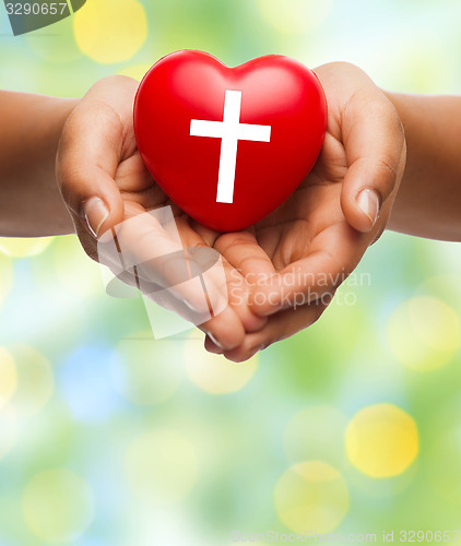 Image of close up of hands holding heart with cross symbol