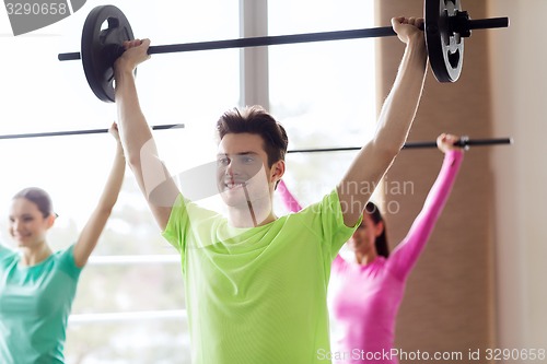 Image of group of people exercising with barbell in gym