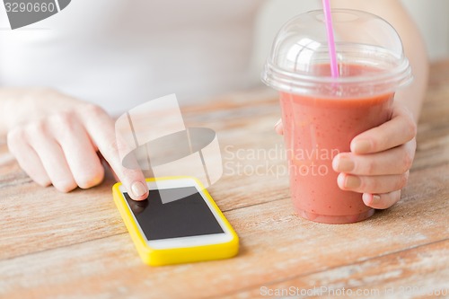 Image of close up of woman with smartphone and smoothie