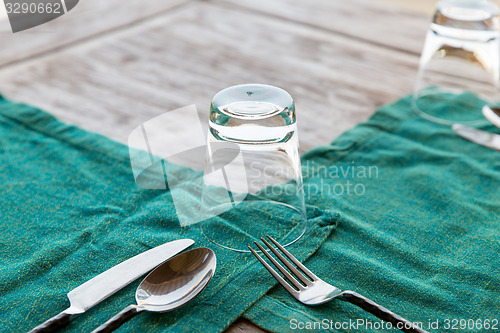 Image of close up of cutlery with glass and napkin on table